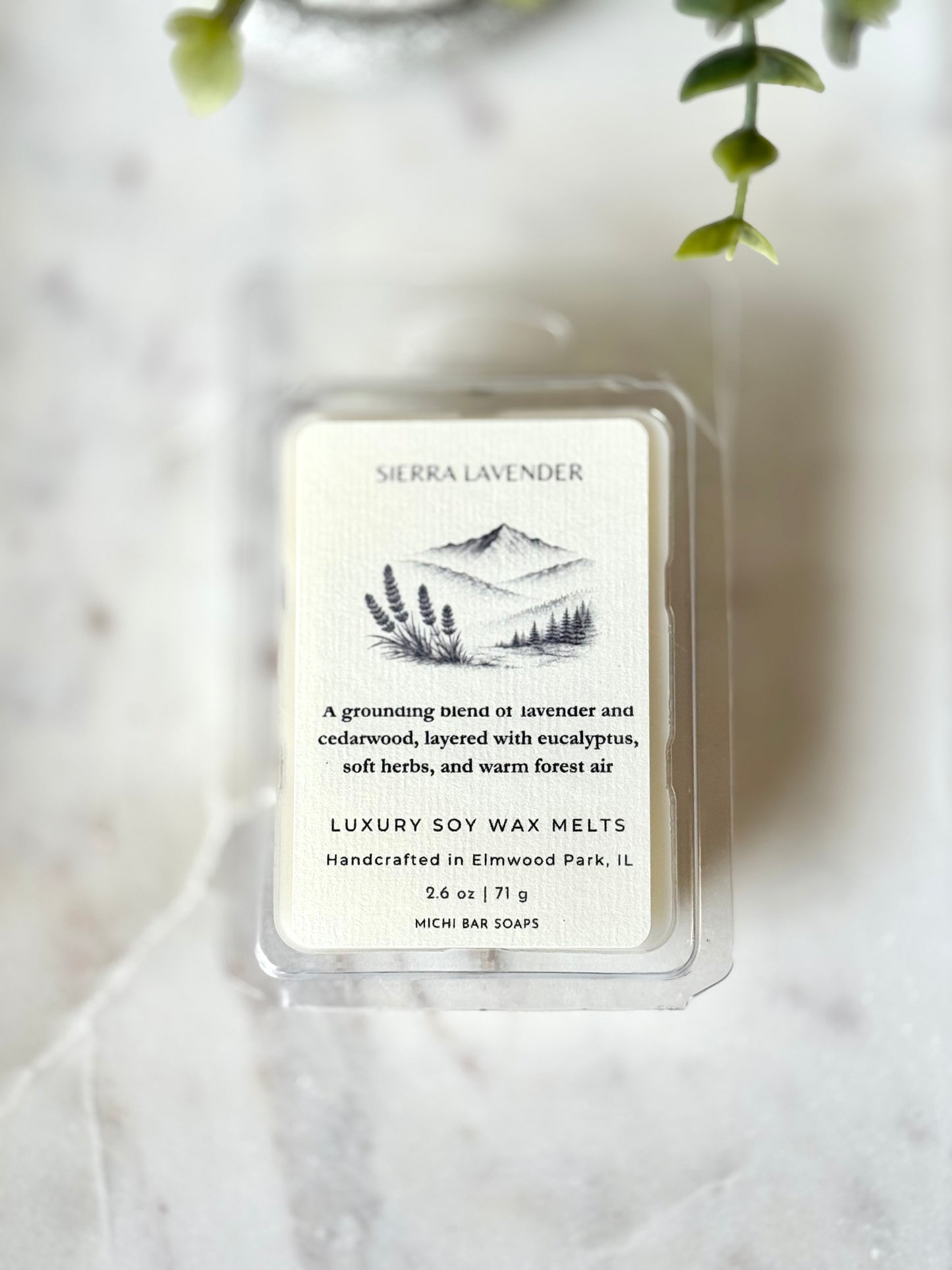 Sierra Lavender wax melt packaging on a marble surface with greenery in the background
