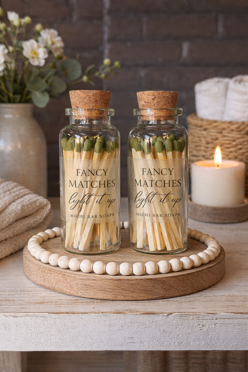 Two glass jars labeled 'Fancy Matches' on a wooden tray with a candle in the background.