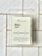 clear clamshell mold with wax scented. cream label that says Bali Surf and scent notes of sea water, amberwood and water lily