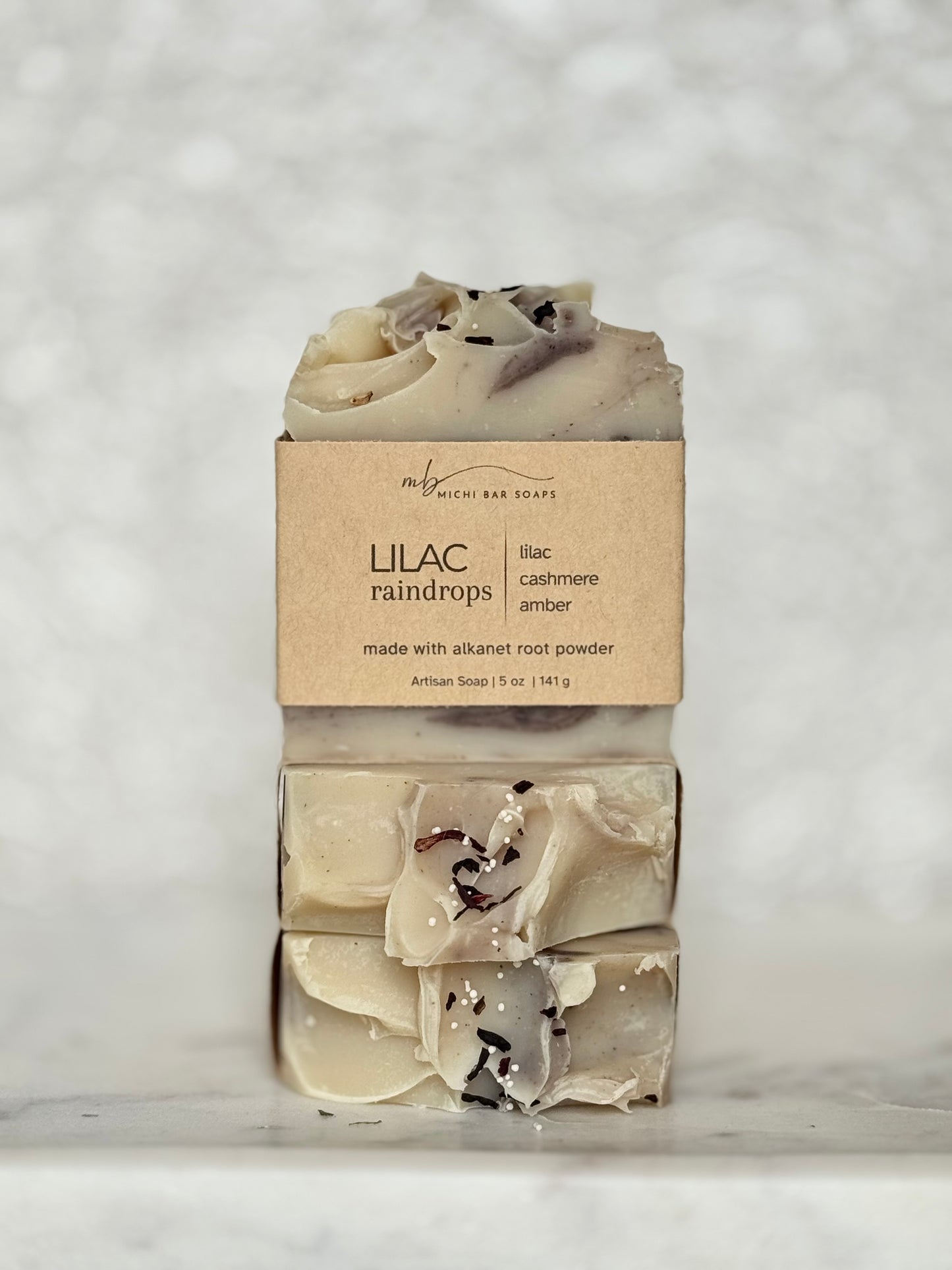 Two bars of soap with a 'Lilac Raindrops' label on a textured white background