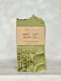 Green soap bar with a brown label on a light gray background