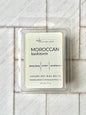 A package of Moroccan Kashmere wax melts, displayed on a white surface. The packaging is predominantly white with product name and scents listed on it.