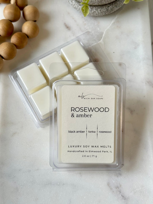 Rosewood & amber soy wax melts in packaging on a marble surface with decorative elements.