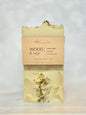 A handmade bar of soap labeled 'WOOD & sage' by Michi Bar Soaps, wrapped in a kraft paper sleeve, set against a light marble background.