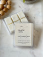 Pack of luxury soy wax melts labeled 'Black Dahlia' on a marble surface with wooden beads.