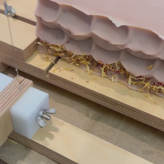 patchouli & sandalwood artisan soap loaf being cut into bars